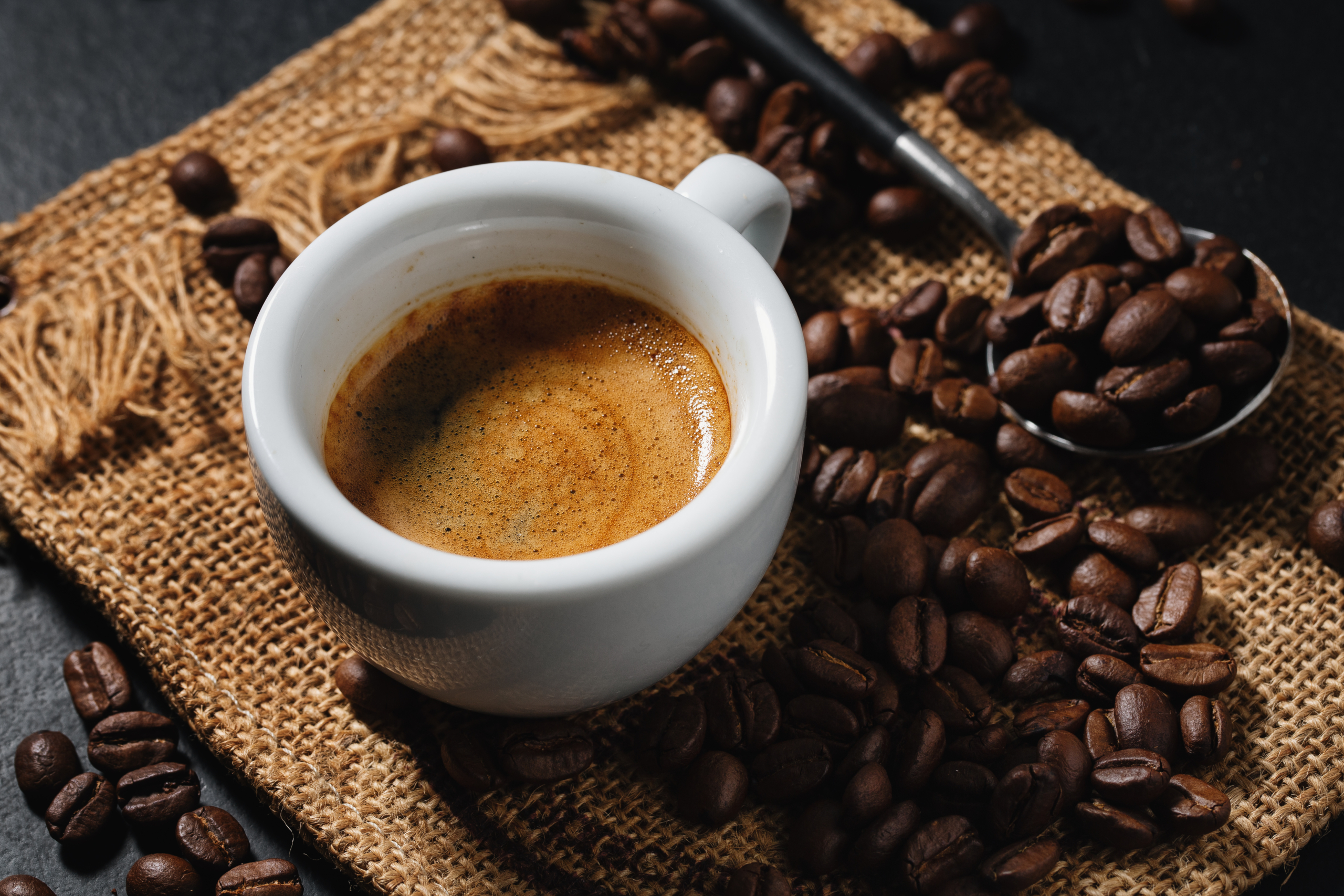 Espressotasse auf einer Matte umgeben von Kaffeebohnen