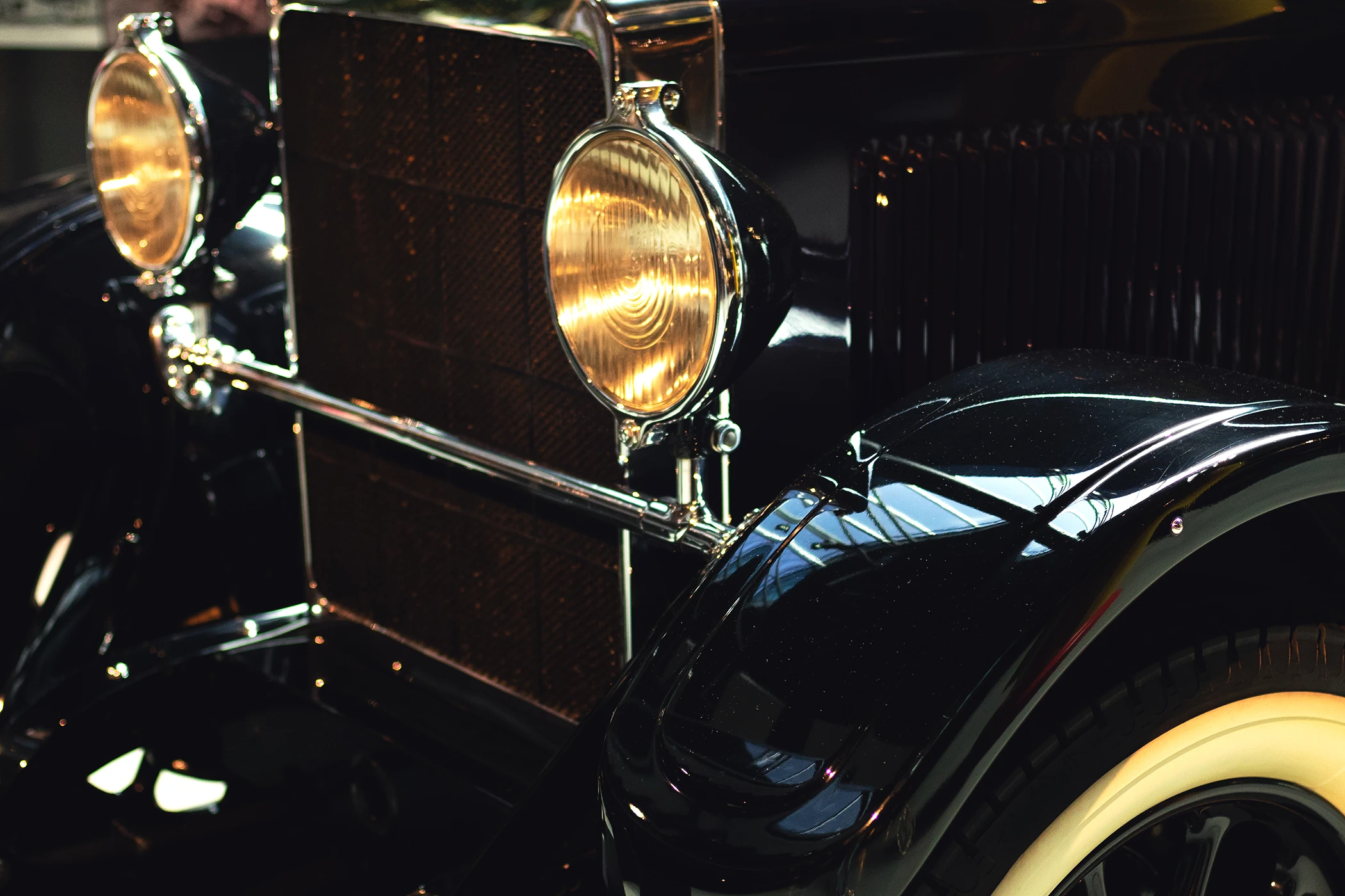 Vorderteil eines schwarzen Oldtimers mit eingeschaltetem Licht